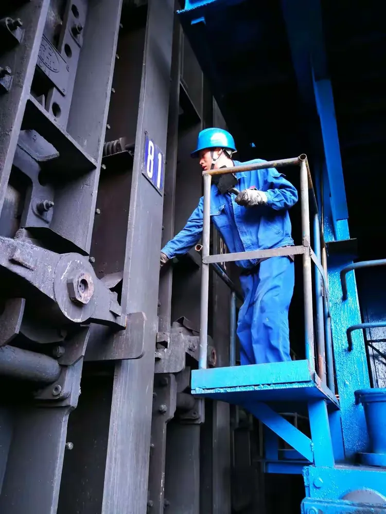 焦炉炉区现场烈日当头,热浪滚滚,炉前工王明亮在2#推焦车上冒着高温的