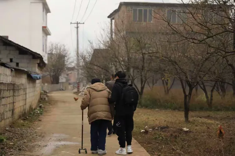 在孙子的搀扶下，蹒跚前行