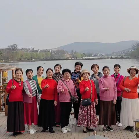 护城河边杨柳青，樱花盛开映桃红。云天在水饮微风，姐妹游园在画中。