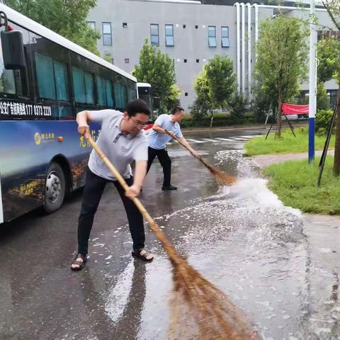 2023年8月1日早上6点51分，卫辉一中两名教师清理道路低凹处的积水