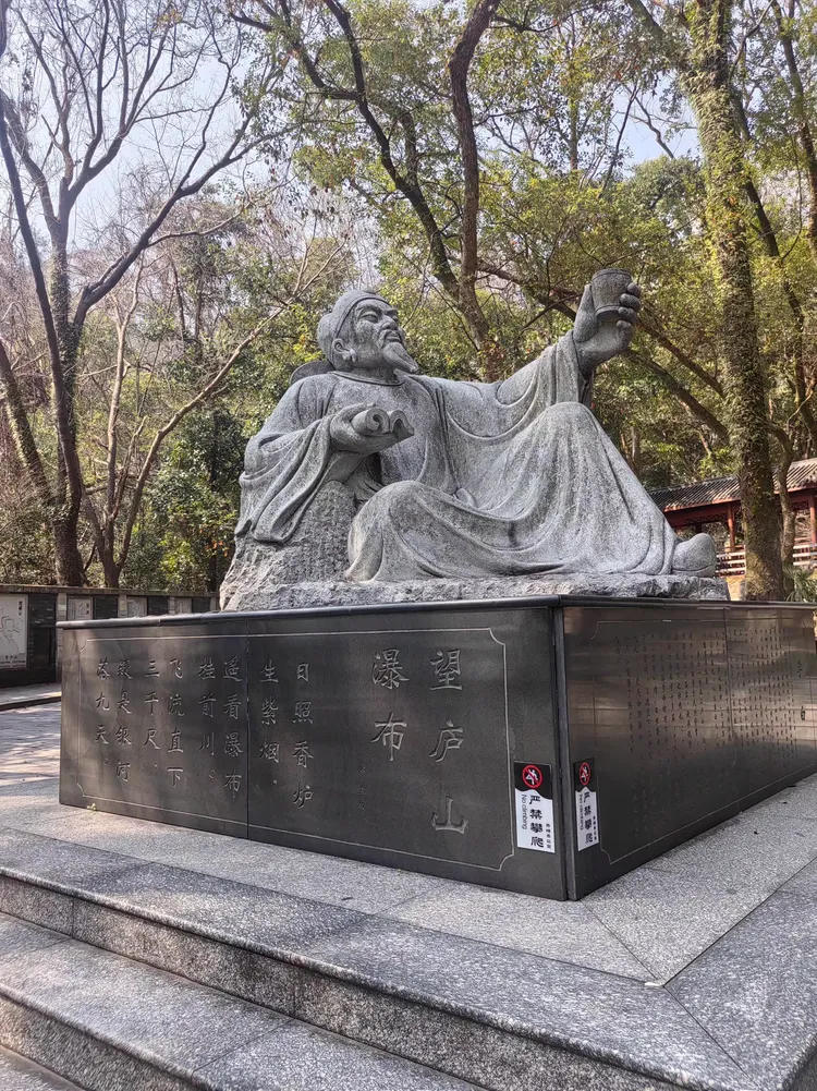 古代文人墨客李白的雕像静静地躺在石头上,手中拿着一本书